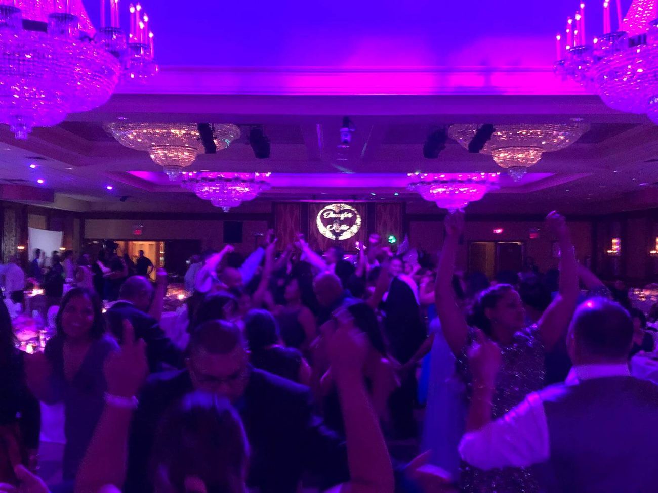 Crowd dancing under pink and purple lights