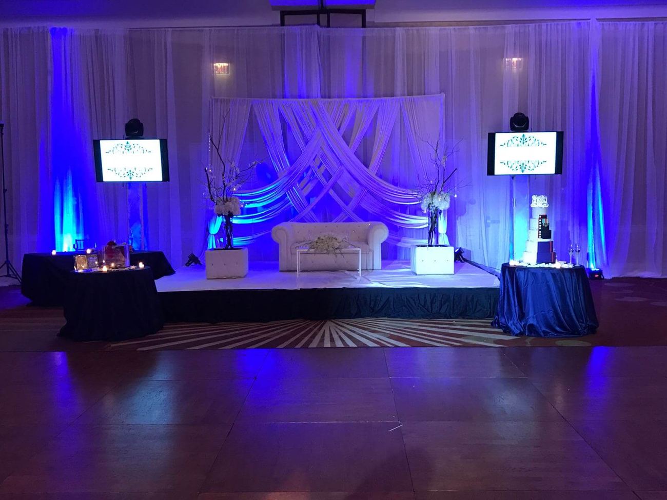 Draped stage and head table setup with blue uplighting